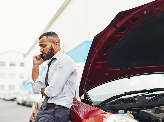 Shot of a man calling roadside assistance after breaking down